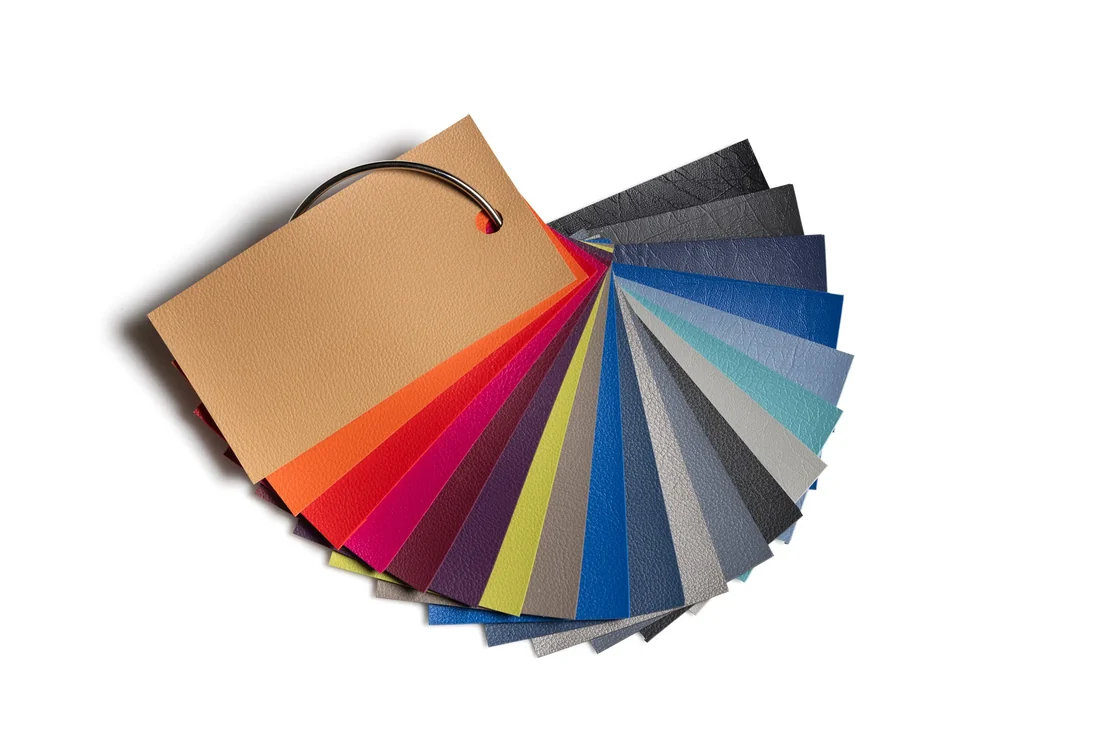 Kleurenwaaier van BQE met kunstlederstalen in zand, oranje, rood, roze, paars, limoen, blauw, turquoise en grijstinten